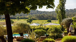 Ein Garten mit Pool, Sitzgelegenheiten im Freien und Blick auf Weinberge im Hintergrund.