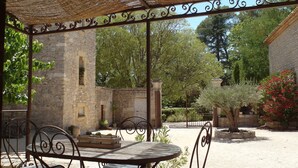 A covered outdoor seating area with stone walls and metal furniture.