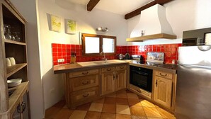 A kitchen with wooden cabinets, a built-in oven, a refrigerator, and a window above the sink.
