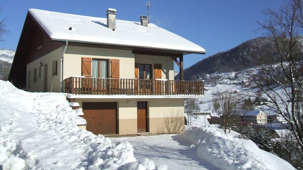 A two-story chalet with a balcony, surrounded by snow-covered landscape and mountains. - Appt in chalet in the heart of the Vosges balloons (Cornimont)