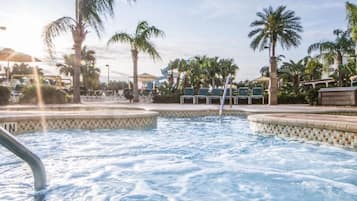 A hot tub area with a tiled edge, palm trees, and lounge chairs.