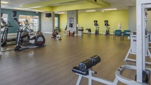 Ein Fitnessraum mit Cardiogeräten, Gewichtstrainern und einem Spiegel.