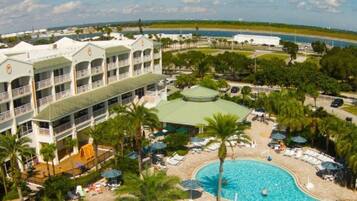 A hotel with multiple balconies, a swimming pool, and a view of the ocean.