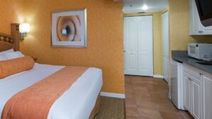 Ein Hotelzimmer mit einem Bett, einem Fernseher, einer Mikrowelle und einer Tür zu einem anderen Raum.