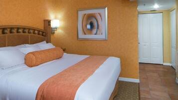 A hotel room with a bed, a television, a microwave, and a door leading to another room.