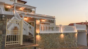 A multi-story building with a stone facade, a white balcony, and a gated entrance. - Rodanthi Hospitality (Faistos)