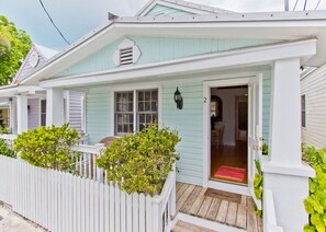 A light blue house with a white porch and a white picket fence.