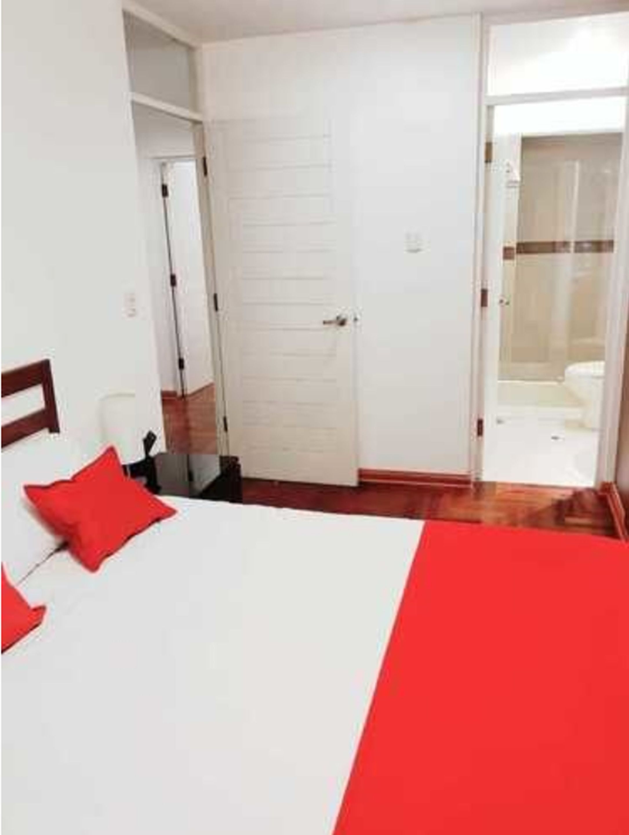 A hotel room with a bed, a desk, and a bathroom visible through an open door.