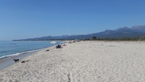 A beach with a clear sky, a sandy shore, and mountains in the background. - Character house, 'U STAZZU' (Ventiseri)