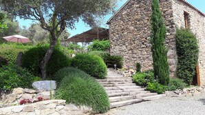 A stone building with a staircase leading to a door, surrounded by lush greenery and a clear blue sky. - Character house, 'U STAZZU' (Ventiseri)