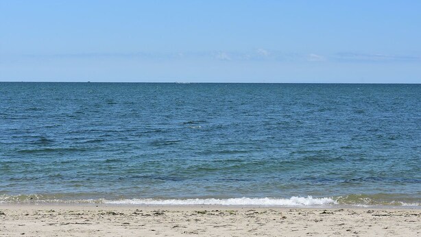 Una spiaggia con acque calme e cielo sereno.