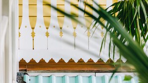 Una pared amarilla y blanca con una barandilla decorativa blanca y una sección de metal corrugado azul.