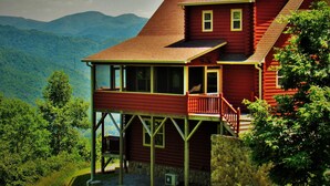 A two-story log cabin with a balcony, set against a mountainous backdrop. - Mtn Views/Large Master Suite/Hot Tub/Wi-Fi (Bryson City)