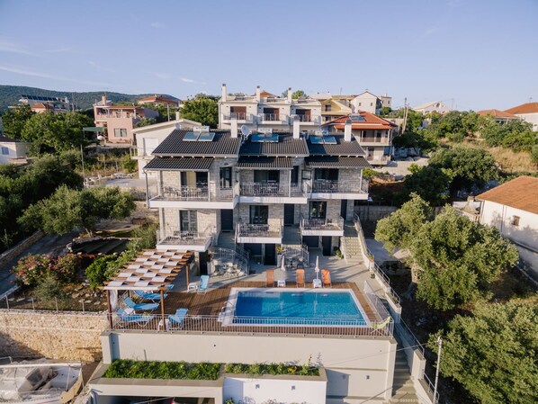 Enjoy a rooftop pool with lounge chairs and umbrellas amidst lush surroundings.