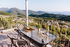 Enjoy a romantic evening on this outdoor space with a glass table, wicker chairs, and a potted plant.