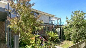 A residential building with a wooden deck, a staircase, and a variety of plants. - Boston Beach House (Lorne)