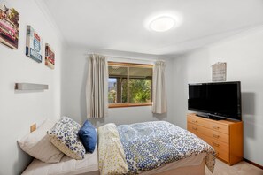 A bedroom with a bed, a television, a window with curtains, and wall decorations.