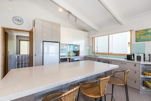 A modern kitchen with a large island, white cabinetry, and a clock on the wall.