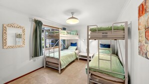 A dormitory room with bunk beds, a window with curtains, a mirror, and a ceiling light. - Boston Beach House (Lorne)