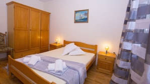 A bedroom with a wooden bed, nightstands with lamps, a wardrobe, and a painting on the wall.