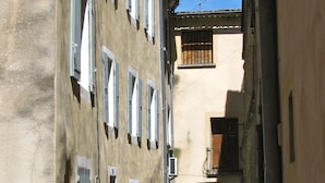 Une rue étroite, bordée de bâtiments des deux côtés, avec de nombreuses fenêtres et une porte bien visible.