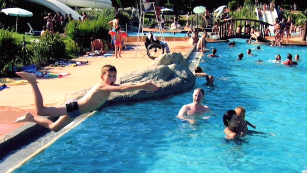 Une piscine avec des personnes dans l’eau et au bord.