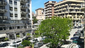 Ein mehrgeschossiges Wohnhaus mit Balkonen, parkgeparkten Autos und einem Baum im Vordergrund.