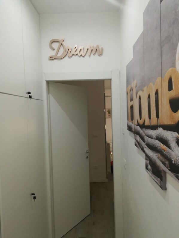 A hallway with a white door, a wall with the word 'Dream' in a cursive font, and a wall with the word 'Home' in a bold, block font. - Casa Vacanze Home (Caltanissetta)