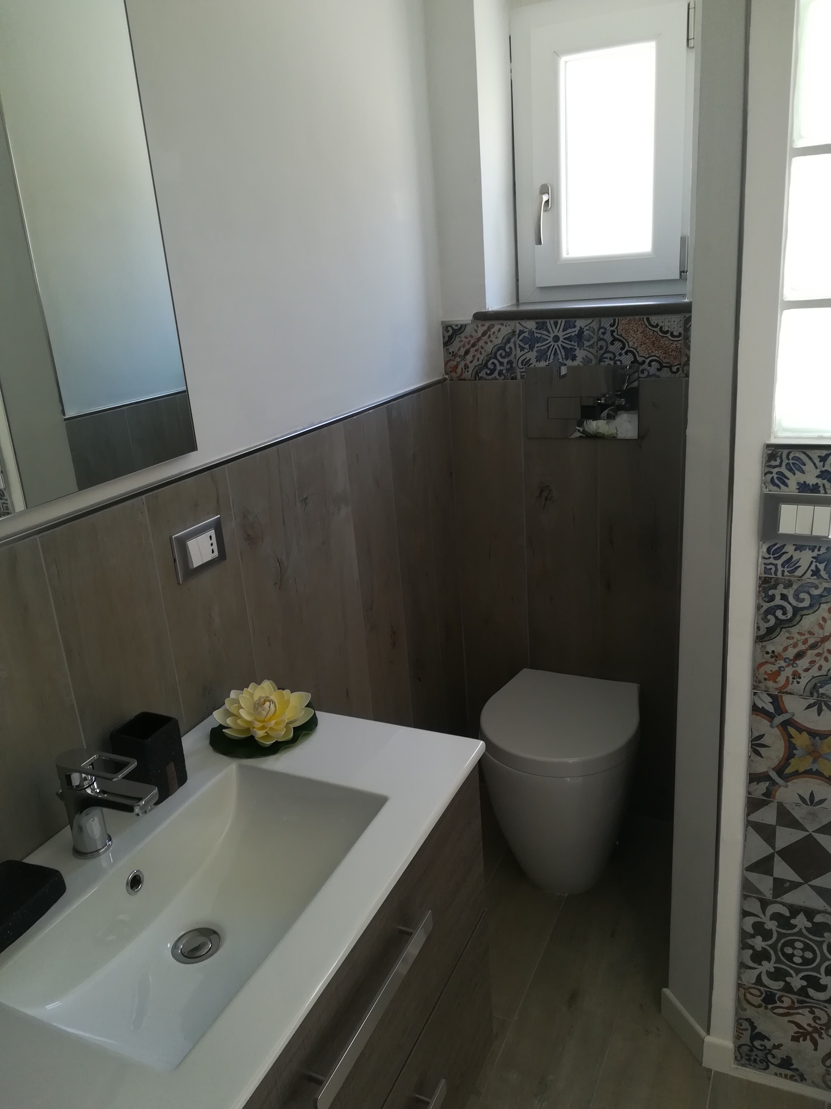 Un baño con lavamanos blanco, inodoro y espejo.