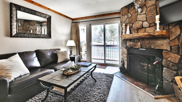 A living room with a stone fireplace, a leather sofa, a coffee table, and a large mirror.