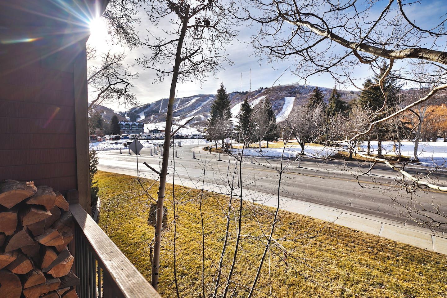 A view from a window overlooking a road with snow-covered hills in the distance.