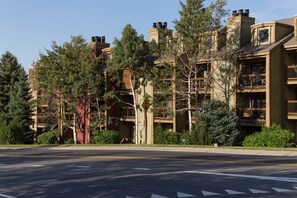A multi-story building with balconies and a parking lot in front.