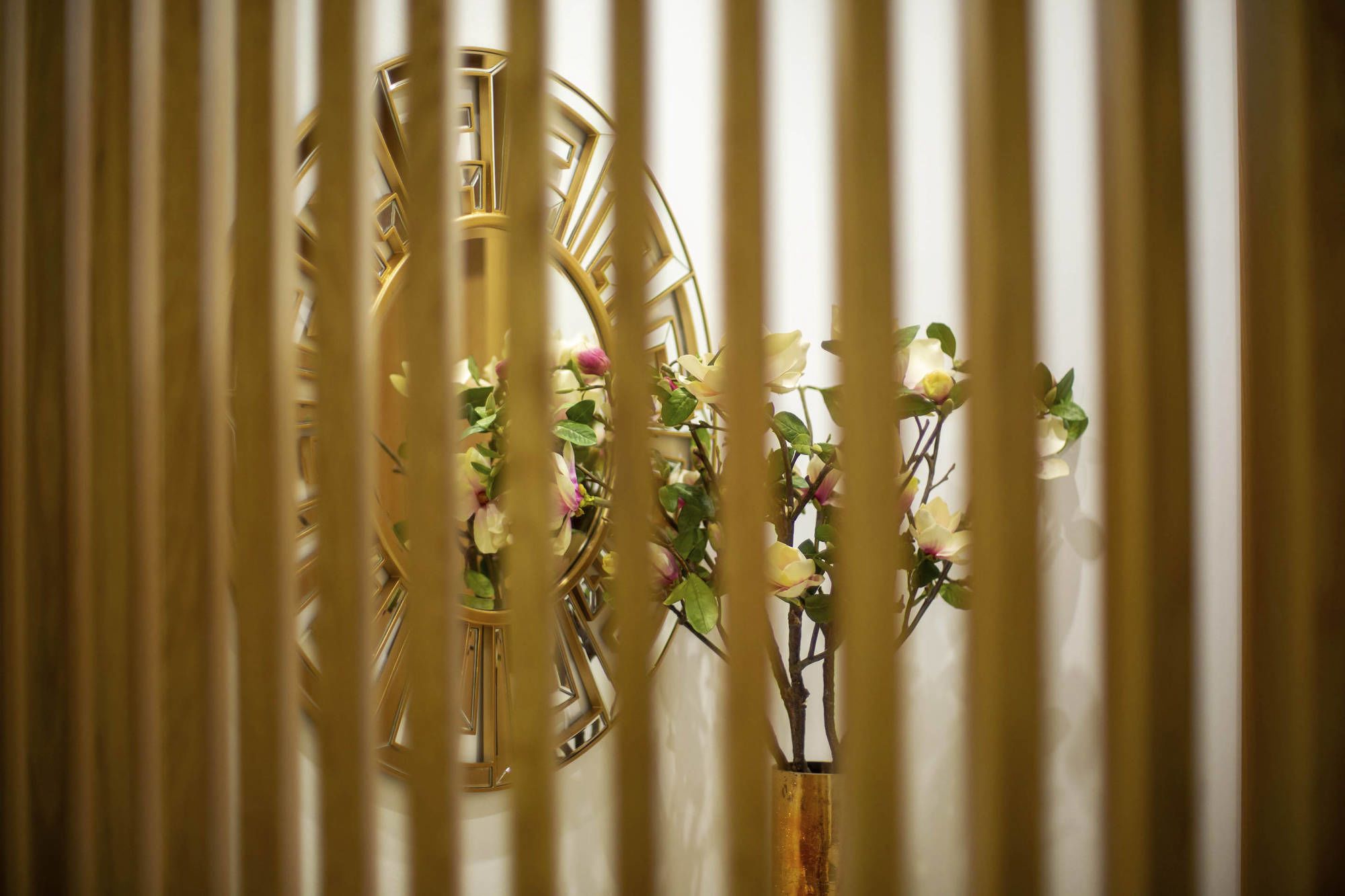 Une pièce avec un panneau décoratif au mur et un vase rempli de fleurs.
