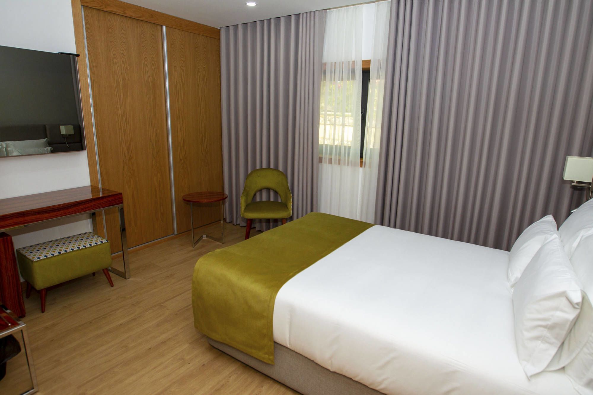 Ein Hotelzimmer mit Bett, Schreibtisch, Stuhl und Fernseher.