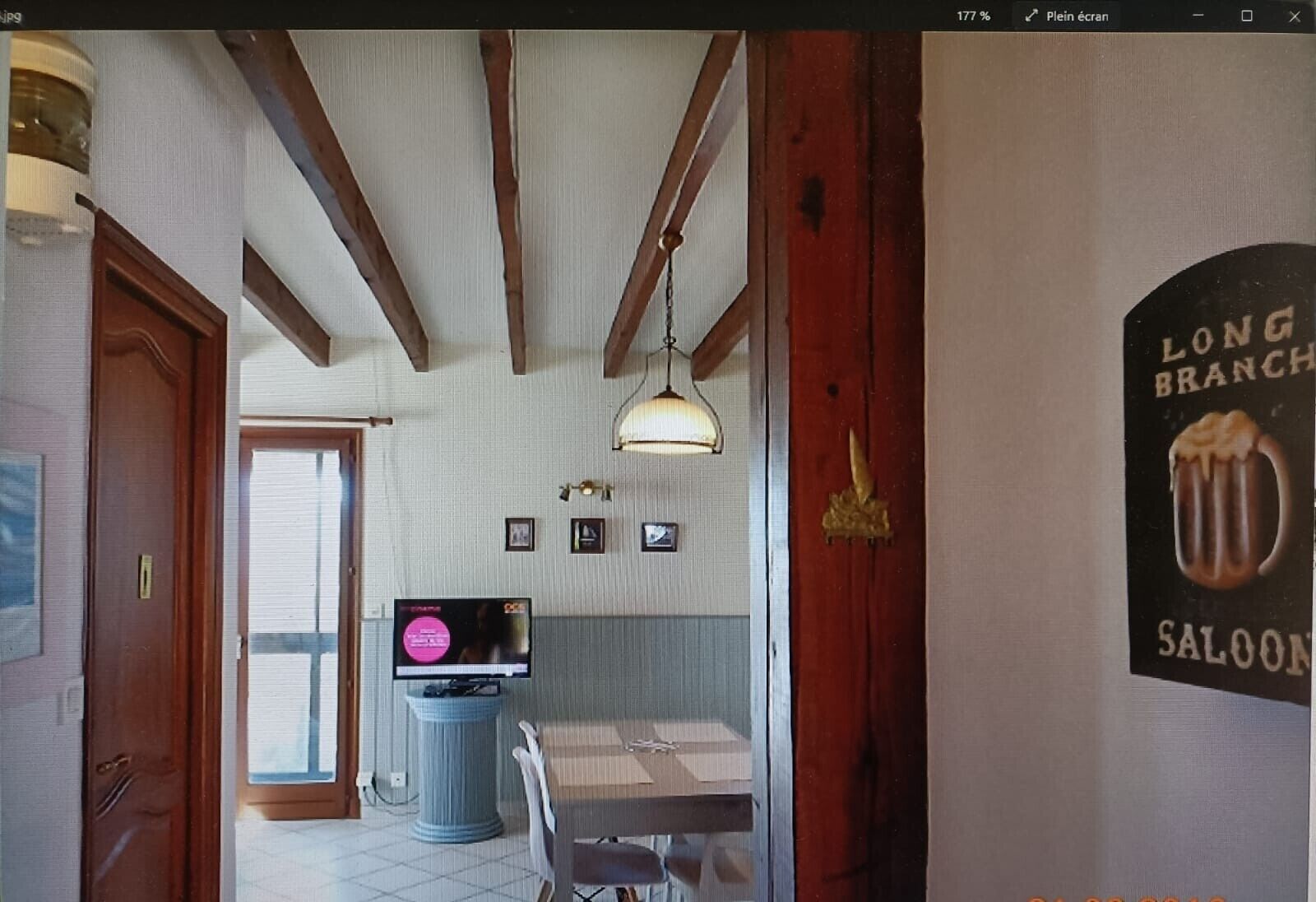 Una habitación con techo de madera, televisor, una mesa de comedor y un cartel en la pared.
