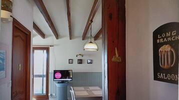 Una habitación con techo de madera, televisor, una mesa de comedor y un cartel en la pared.