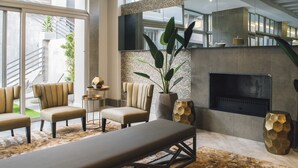 Un área de descanso moderna con chimenea, asientos cómodos y una planta grande.