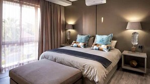 Un dormitorio moderno con una cama grande, una mesita de noche, un equipo de aire acondicionado y vistas al exterior.