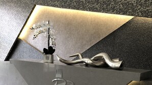 Un mostrador de recepción moderno con diseño geométrico, un logotipo y una escultura decorativa.
