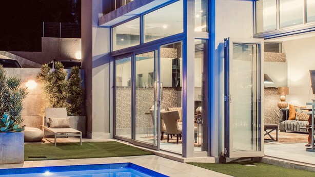 Una casa moderna de dos pisos con piscina, amplios ventanales y un espacio exterior bien iluminado.