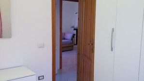 A bedroom with a bed, a wardrobe, and a door leading to another room. - Holidays in San Teodoro (San teodoro)