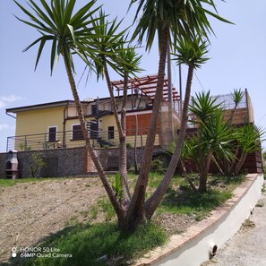 A yellow building with a balcony, surrounded by palm trees. - CASA ELISABETTA 2: magnificent sea view and comfort not far from Naples (Caprioli di Pisciotta)