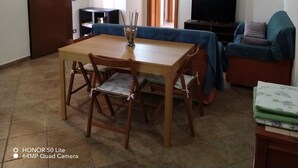 Een woonkamer met een houten eettafel, stoelen, een bank, een televisie en een open haard.