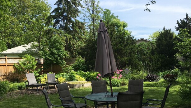 Un patio al aire libre con una mesa redonda y cuatro sillas, bordeado por un marco de ladrillo.