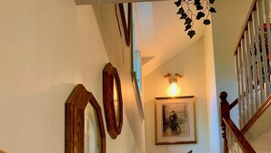 Una escalera con alfombra estampada, barandillas de madera y un cuadro en la pared.