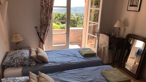 A bedroom with two beds, a large window with a view of greenery, a lamp, and a mirror. - Villa with swimming pool in the Gulf of SAINT-TROPEZ (La Croix-Valmer)