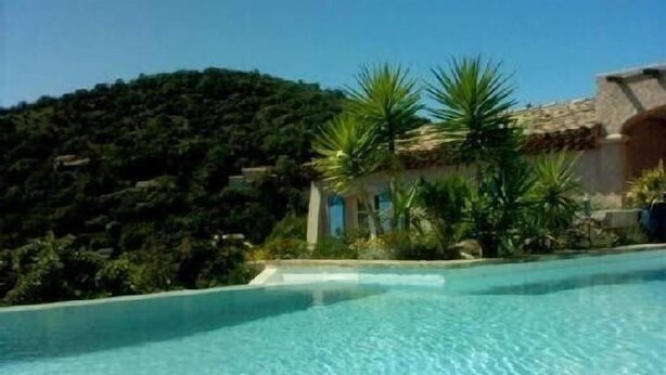 A clear swimming pool surrounded by lush greenery and a hillside. - Villa with swimming pool in the Gulf of SAINT-TROPEZ (La Croix-Valmer)