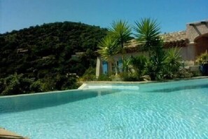 A clear swimming pool surrounded by lush greenery and a hillside. - Villa with a Pool in the Bay of SAINT-TROPEZ (La Croix-Valmer)