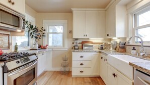 A kitchen with white cabinets, a stove, a microwave, a sink, and a window. - Gorgeous 3 bed/ 2 bath home in the heart of Sellwood! Walk to everything! (Portland)