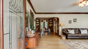 A spacious living room with a wooden floor, a leather sofa, and a dining area with a wooden table and chairs. - Gorgeous 3 bed/ 2 bath home in the heart of Sellwood! Walk to everything! (Portland)
